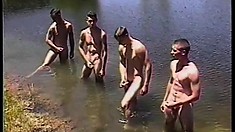 Four young studs take a swim in the lake and stroke their big cocks