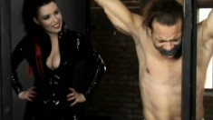 Mistress Anastasia Pierce ties her slave up to bars and punishes him
